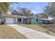 View of single-story home with long driveway leading to attached one-car garage at 245 Faithway Dr, Seffner, FL 33584