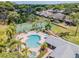 Aerial view of a community pool, spa, and tennis court, surrounded by mature trees and lush landscaping at 2473 Bentley Dr, Palm Harbor, FL 34684