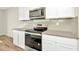 A modern kitchen features stainless steel oven and microwave, complemented by white cabinets and gray backsplash at 31818 Treasure Dock Isle, Wesley Chapel, FL 33545