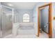 Bathroom features a shower with glass door, and a separate soaking tub under an arched window for natural light at 3917 Appletree Dr, Valrico, FL 33594