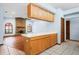 Open kitchen view with breakfast bar, wood cabinets, tile floors, and access to a living space with brick fireplace at 3917 Appletree Dr, Valrico, FL 33594