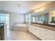 Bright bathroom featuring a bathtub, walk-in shower, double vanity, and natural light from the window at 4132 Woods Rider Loop, Odessa, FL 33556