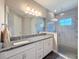 Main bathroom with a double vanity, granite counters, and a walk-in shower with glass door at 4132 Woods Rider Loop, Odessa, FL 33556