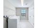 Laundry room with a washer, dryer, storage, tile floors, and natural light from the window at 4132 Woods Rider Loop, Odessa, FL 33556