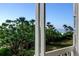 Balcony view showing lush foliage and swaying palm trees, with a glimpse of the blue ocean at 6500 Sunset Way # 202, St Pete Beach, FL 33706