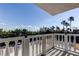 Balcony view showing lush trees and distant cars in a serene outdoor setting with white railings at 6500 Sunset Way # 202, St Pete Beach, FL 33706