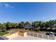 Balcony view featuring verdant trees, manicured lawns, and serene tennis courts under a vast blue sky at 6500 Sunset Way # 202, St Pete Beach, FL 33706