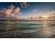 Waves meet the sandy shore under a beautiful, cloud-filled sky at this relaxing beach location at 6500 Sunset Way # 202, St Pete Beach, FL 33706