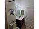 Bathroom with updated vanity, framed mirror with decorative lights, and tiled shower at 920 Regal Manor Way, Sun City Center, FL 33573