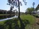 A serene pond view, accented by lush greenery, multi-story buildings, and a sunny sky at 1 Quails Run Blvd # 2, Englewood, FL 34223