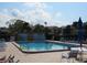 Relaxing community pool surrounded by lounge chairs and lush greenery on a sunny day at 1 Quails Run Blvd # 2, Englewood, FL 34223