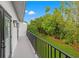 A balcony with black metal railings overlooks a lush green yard with mature landscaping and a blue sky at 1118 S Moody Ave, Tampa, FL 33629