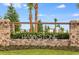 Beautiful stone community entrance sign with lush landscaping and palm trees at 12515 Horseshoe Bend Dr, Lithia, FL 33547