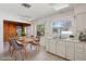 Bright kitchen features white cabinets, tile floor, table for four, and a view to a wood-paneled dining area at 1910 Rainbow Dr, Clearwater, FL 33765