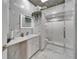 Luxurious bathroom featuring marble walls, a stylish vanity, an illuminated mirror, and a modern glass-enclosed shower at 3106 Lila St, Tampa, FL 33610