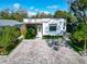 Charming single-story home with modern design, well-manicured lawn, brick driveway, and lush landscaping at 3106 Lila St, Tampa, FL 33610