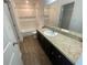 Bright bathroom featuring a shower-tub combo, dark cabinets, and a large mirror at 35220 White Water Lily Way, Zephyrhills, FL 33541
