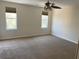 Bright bedroom featuring carpeted floors, two windows, and a ceiling fan at 415 Bayou Village Dr, Tarpon Springs, FL 34689