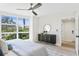 Bright bedroom featuring a large window, ceiling fan, and stylish cabinet with a round mirror at 4951 Bacopa S Ln # 103, St Petersburg, FL 33715