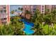 Beautifully landscaped pool area with tropical trees and view of a resort-style building and the ocean at 4951 Bacopa S Ln # 103, St Petersburg, FL 33715