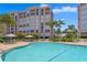 Outdoor swimming pool surrounded by lush tropical landscape, brick pavers and a condo building at 4951 Bacopa S Ln # 103, St Petersburg, FL 33715