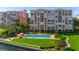Elevated view of the pool area with manicured green space and umbrella seating near waterfront condos at 4951 Bacopa S Ln # 103, St Petersburg, FL 33715
