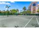 Spacious tennis court with green surface, set against a backdrop of tropical foliage and building at 4951 Bacopa S Ln # 103, St Petersburg, FL 33715