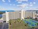 Condo building with tennis courts, parking, and nearby body of water with lush greenery at 5915 Sea Ranch Dr # 703, Hudson, FL 34667