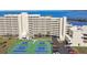 Condo building with tennis courts and parking, near a body of water with lush greenery at 5915 Sea Ranch Dr # 703, Hudson, FL 34667