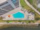 Aerial view of sparkling pool with lounge chairs and lush landscaping overlooking the bay at 5915 Sea Ranch Dr # 703, Hudson, FL 34667