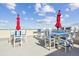 A roof top patio has several tables and chairs with bright blue fabric and red umbrellas for an enjoyable afternoon at 5915 Sea Ranch Dr # 703, Hudson, FL 34667