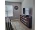 Well-lit bedroom showcasing a dresser, large television, and framed photos at 6421 Banyan Blvd # 302, New Port Richey, FL 34652