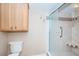 Updated bathroom featuring a toilet and a shower with glass doors, plus a wooden cabinet and tiled walls at 690 Island Way # 404, Clearwater Beach, FL 33767