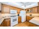 Kitchen with wood cabinets, white appliances, and a ceiling fan for added comfort and style at 690 Island Way # 404, Clearwater Beach, FL 33767