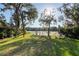 Spacious backyard with lush green grass, mature trees, a cozy fire pit, and a scenic view of the lake at 732 June Lake Ln, Brandon, FL 33510