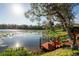 Scenic lake view featuring a private wooden dock, lush landscaping, and a small boat at 732 June Lake Ln, Brandon, FL 33510