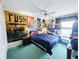 Bedroom with ceiling fan, blue carpet, and decorated with posters at 11040 Flicker Rd, Brooksville, FL 34613