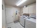 Functional laundry room with washer, dryer, sink, storage cabinets, and tile flooring at 11040 Flicker Rd, Brooksville, FL 34613