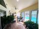 Bright sunroom featuring a tile floor, ceiling fan, and lovely wicker furniture overlooking the pool at 11040 Flicker Rd, Brooksville, FL 34613