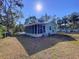 Exterior view of the house including a screened-in porch and overgrown grass at 1276 Sedeeva N Cir, Clearwater, FL 33755