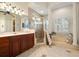 Bright bathroom with a glass enclosed shower, soaking tub, wood vanity, and tile flooring at 1724 Amberwynd W Cir, Palmetto, FL 34221