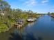 Picturesque waterfront featuring multiple docks, with boat lifts, along a serene canal, and lush, mature trees at 1724 Amberwynd W Cir, Palmetto, FL 34221