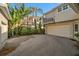 Exterior view showcasing the garage, balcony, lush tropical landscaping, and brick driveway at 1724 Amberwynd W Cir, Palmetto, FL 34221