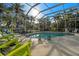 Screened-in pool with inviting chairs and lush tropical landscaping creates a relaxing outdoor oasis at 1724 Amberwynd W Cir, Palmetto, FL 34221