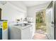 Bright laundry room featuring modern washer and dryer, water heater, and outside access at 1801 E Mcberry St, Tampa, FL 33610