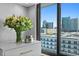 Charming bedroom detail showcasing vase of flowers, dresser, candle, and city skyline view at 201 W Laurel St # 1006, Tampa, FL 33602