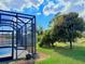 Landscaped backyard view of screened-in pool and lush green trees at 2329 Como St, Port Charlotte, FL 33948