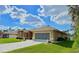 Well-maintained home with a spacious driveway, a two-car garage, and lush green landscaping at 2329 Como St, Port Charlotte, FL 33948