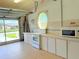 Garage kitchen features classic white cabinets, appliances, and a view to the outside at 2329 Como St, Port Charlotte, FL 33948