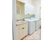A practical laundry room equipped with overhead cabinets, a utility sink, and modern washing and drying machines at 2329 Como St, Port Charlotte, FL 33948